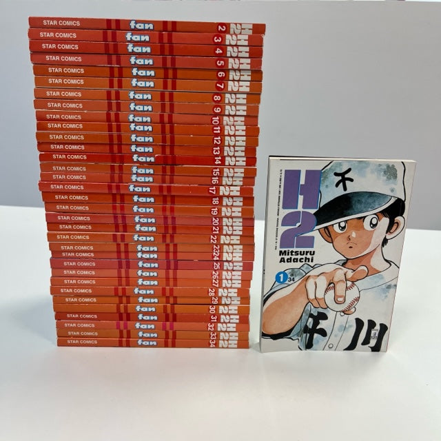 H2 Manga Mitsuru Adachi Star Comics Serie Completa 1-34, personaggio in divisa da baseball su copertina numero 1 ed altri numeri impilati in ordine, costa arancione/rosso