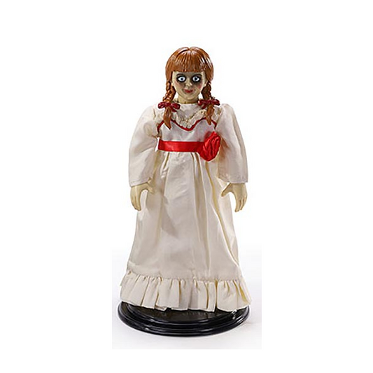 Statuina del personaggio bambola Annabelle dal film The Conjuring, con vestito bianco e nastro rosso.