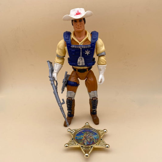 bravestarr john marshall della filmation anno 1986, cowboy spaziale, cappello bianco, pettorina blu, camicia crema e pantalone marrone, con armi e stella